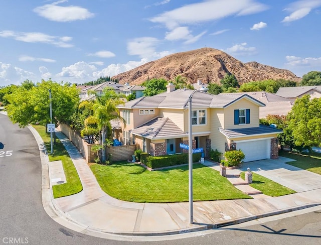 traditional-style home with concrete driveway, a tile roof, fence, a mountain view, and a front lawn