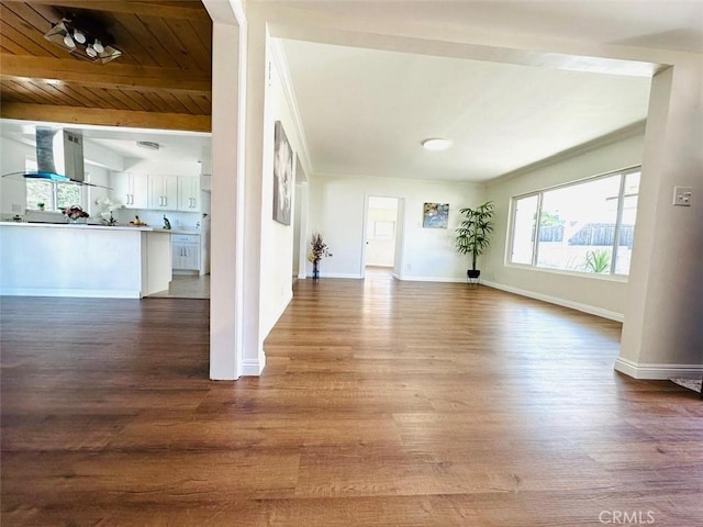 unfurnished living room with dark wood finished floors, wood ceiling, beamed ceiling, and baseboards