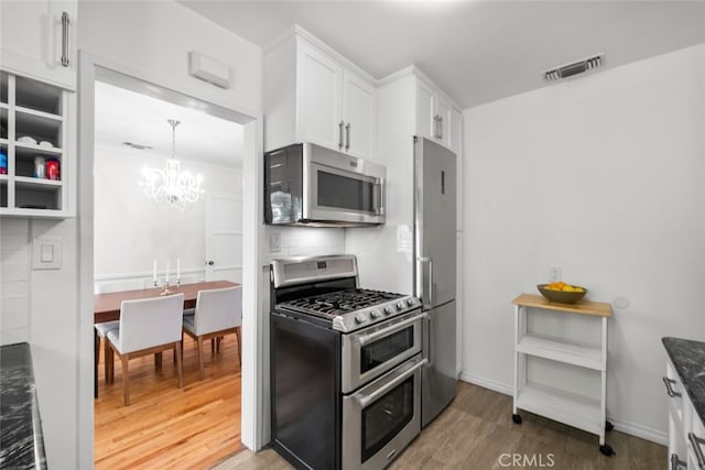 kitchen with visible vents, appliances with stainless steel finishes, light wood-style floors, white cabinetry, and backsplash