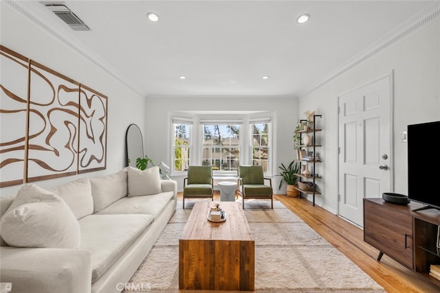 living area featuring light wood-style floors, recessed lighting, visible vents, and crown molding