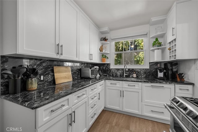 kitchen featuring open shelves, stainless steel range, white cabinets, and decorative backsplash