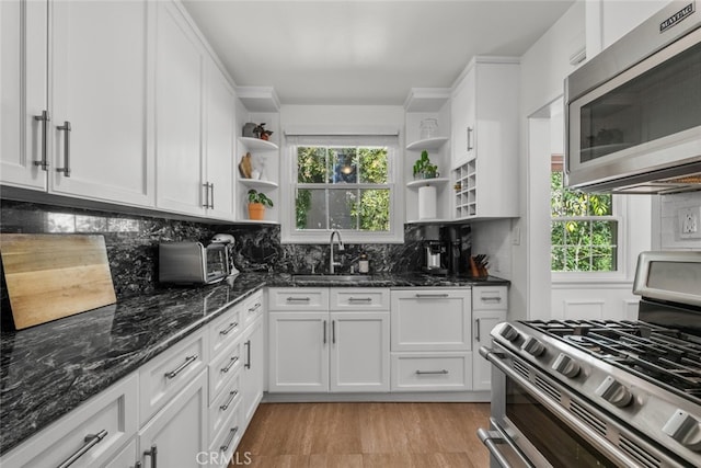 kitchen featuring open shelves, backsplash, stainless steel appliances, and a sink