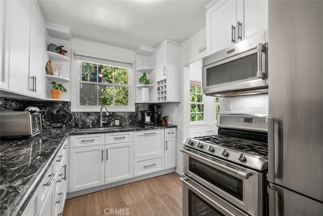 kitchen with a sink, white cabinets, appliances with stainless steel finishes, open shelves, and tasteful backsplash