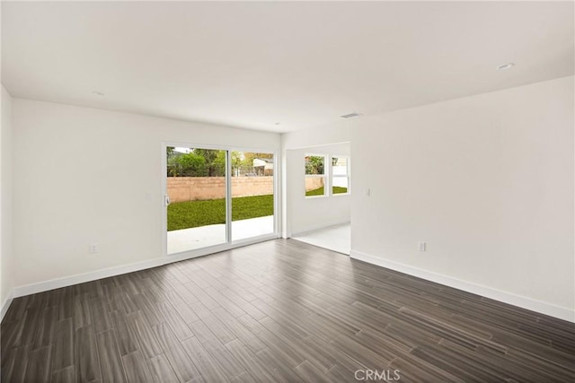 spare room featuring visible vents, baseboards, and dark wood finished floors