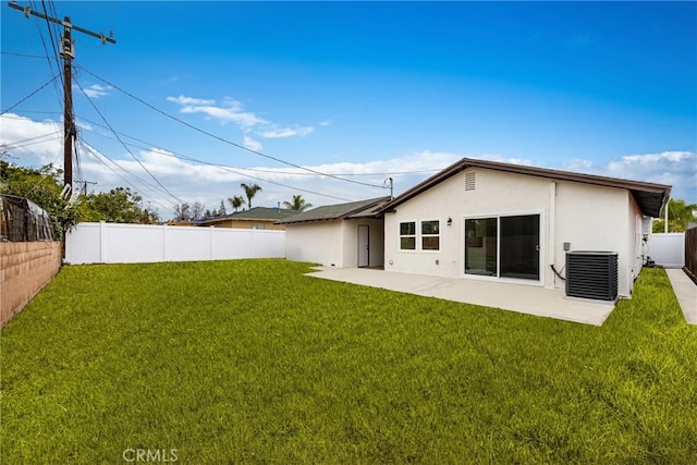 back of property featuring a yard, stucco siding, a patio area, central AC, and a fenced backyard