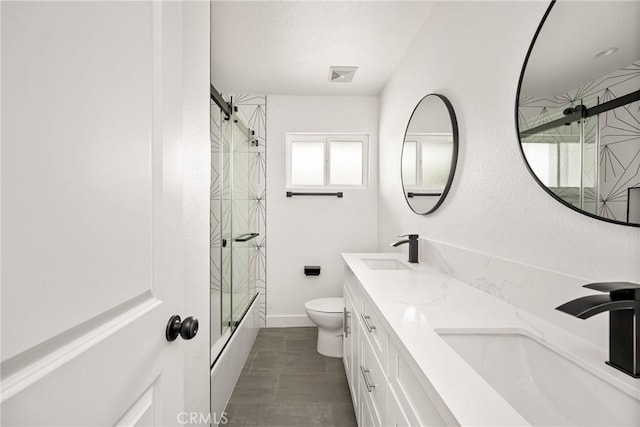 bathroom with toilet, double vanity, visible vents, and a sink