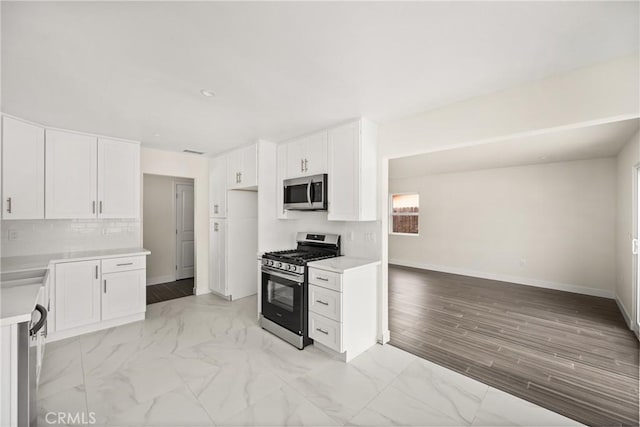 kitchen with white cabinets, tasteful backsplash, stainless steel appliances, and light countertops