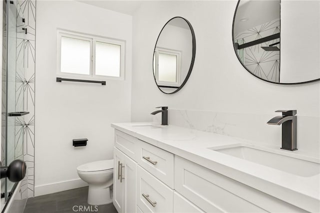 full bath with a shower, double vanity, toilet, a sink, and baseboards