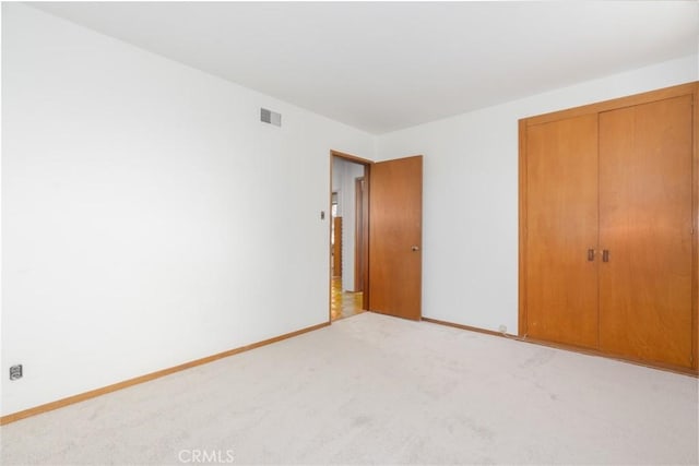 unfurnished bedroom featuring carpet floors, a closet, visible vents, and baseboards