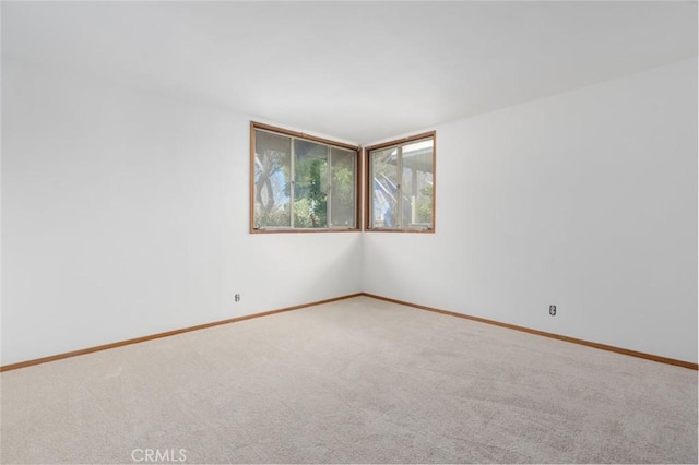 carpeted empty room featuring baseboards