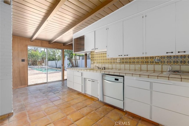 kitchen with tile countertops, decorative backsplash, wood ceiling, white cabinetry, and a sink