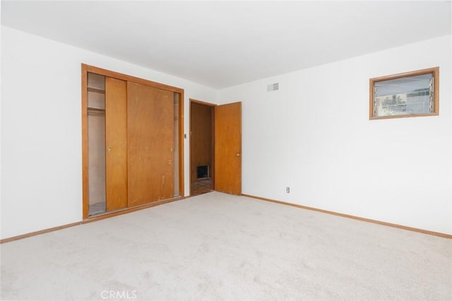 unfurnished bedroom featuring carpet, visible vents, baseboards, and a closet