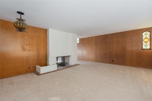 unfurnished living room with carpet flooring, a fireplace, and wood walls