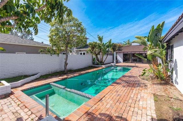 view of swimming pool with a pool with connected hot tub, a fenced backyard, and a patio