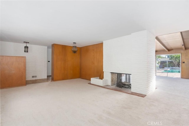 unfurnished living room with carpet floors, a brick fireplace, and beamed ceiling