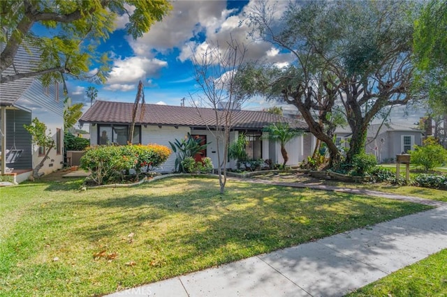 single story home featuring a tile roof, a front lawn, and central air condition unit