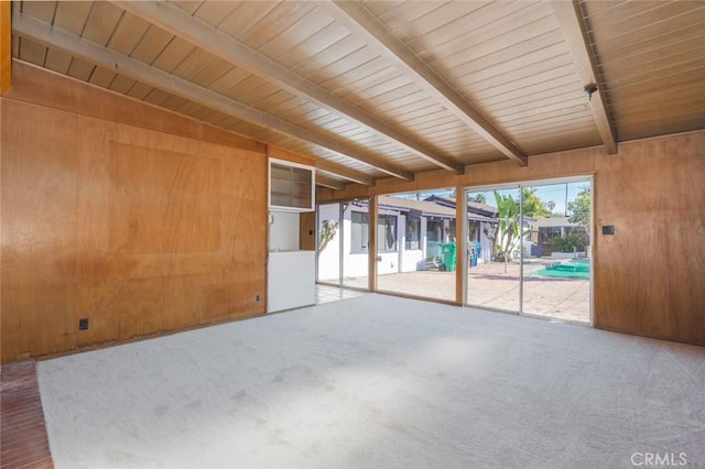 unfurnished room with wood walls, wooden ceiling, carpet flooring, and beam ceiling