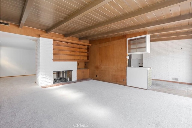 unfurnished living room featuring carpet floors, a brick fireplace, visible vents, and beam ceiling