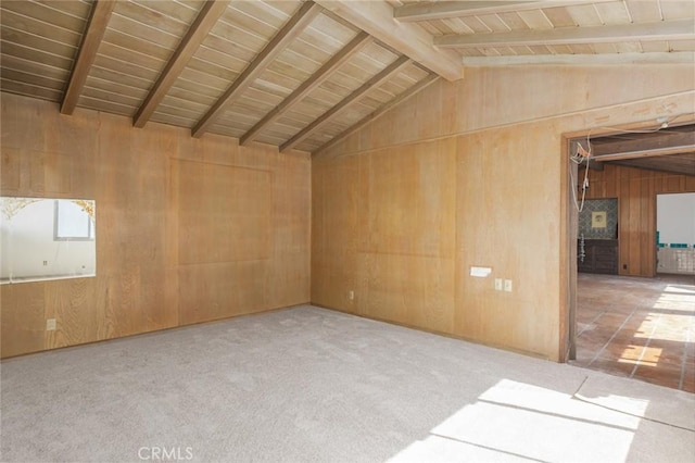 unfurnished room featuring lofted ceiling with beams, wood walls, and carpet