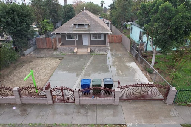 bungalow-style house featuring a fenced front yard, a gate, and concrete driveway