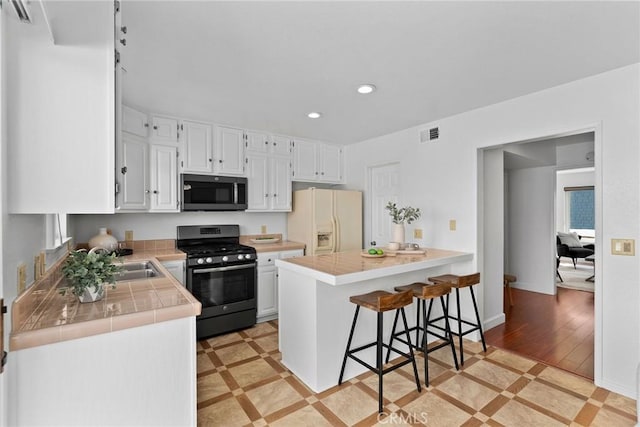 26B Surfside Ave, Surfside, CA 90743 - kitchen with appliances with stainless steel finishes, recessed lighting, inlaid floor details, tile counters, and white cabinetry