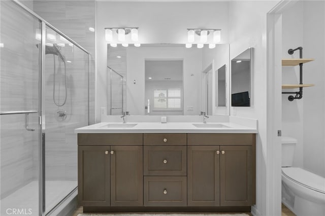 full bathroom featuring double vanity, toilet, a shower stall, and a sink