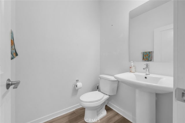 bathroom with baseboards, a sink, toilet, and wood finished floors