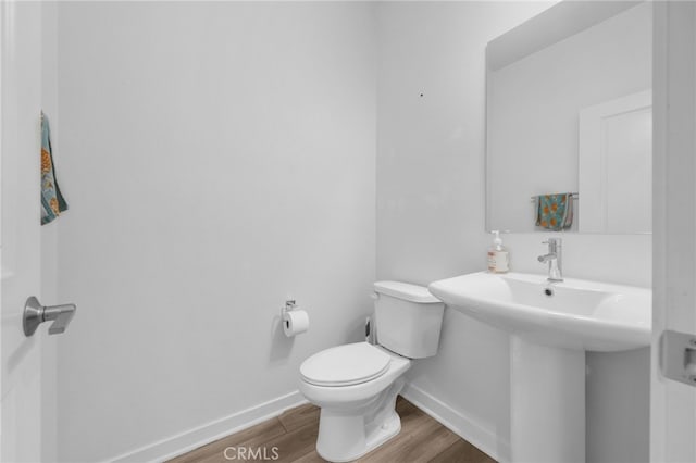 bathroom with a sink, baseboards, toilet, and wood finished floors