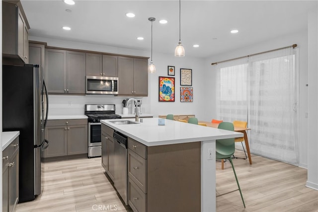 kitchen with light countertops, stainless steel appliances, a sink, and light wood finished floors