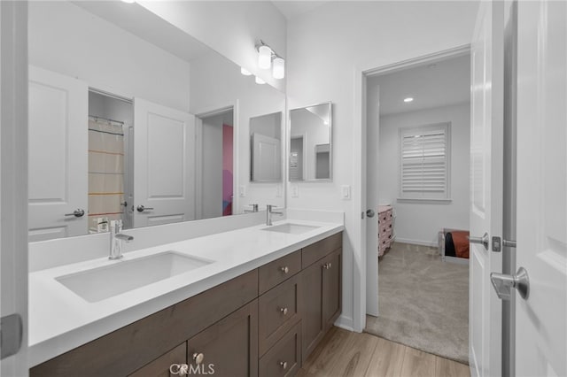 full bath featuring double vanity, baseboards, a sink, and wood finished floors