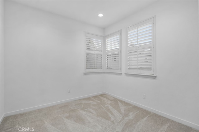 spare room with recessed lighting, light carpet, and baseboards