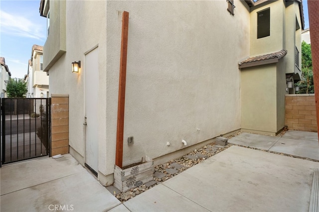 view of home's exterior with a patio, a tiled roof, a gate, fence, and stucco siding