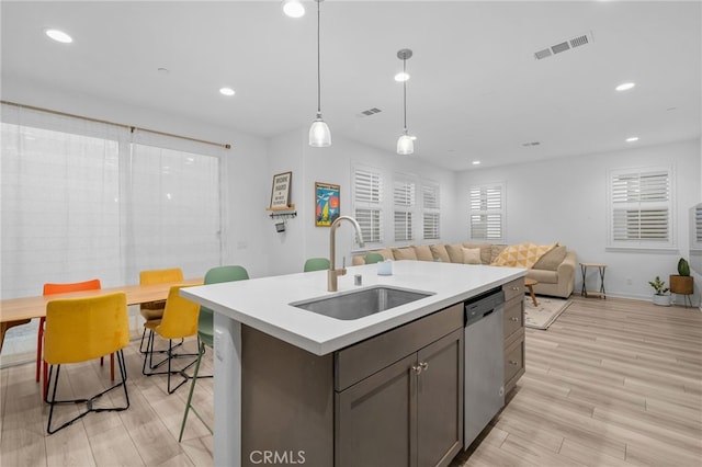 kitchen with stainless steel dishwasher, visible vents, light wood-style floors, light countertops, and a sink