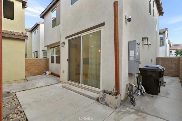 rear view of house featuring fence, stucco siding, and a patio area