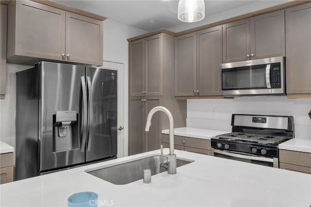 kitchen featuring appliances with stainless steel finishes, light countertops, and a sink