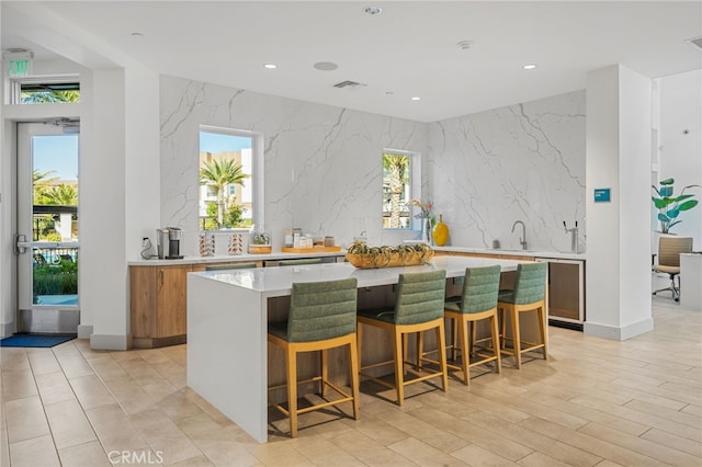 kitchen featuring light countertops, brown cabinetry, a kitchen bar, and a kitchen island