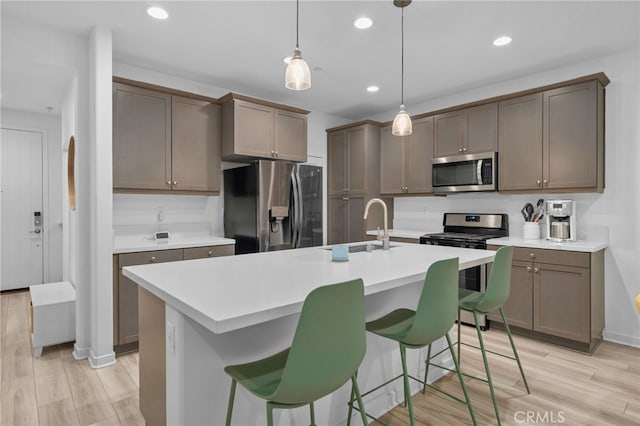 kitchen with light countertops, stainless steel appliances, light wood finished floors, and a sink