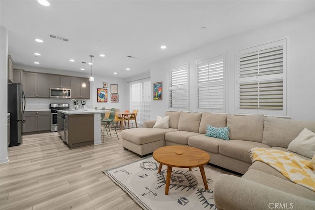 living room featuring light wood-type flooring, visible vents, and recessed lighting