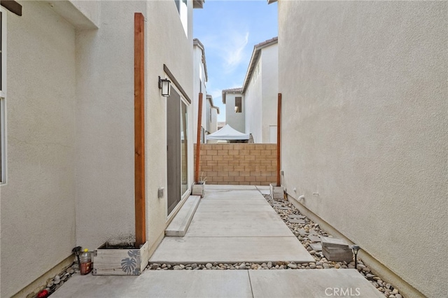 view of side of property with fence, a patio, and stucco siding