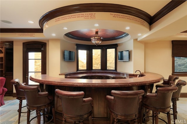 bar featuring recessed lighting, a community bar, baseboards, a tray ceiling, and crown molding