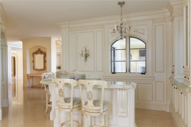 dining room with an inviting chandelier, light tile patterned floors, a decorative wall, and crown molding