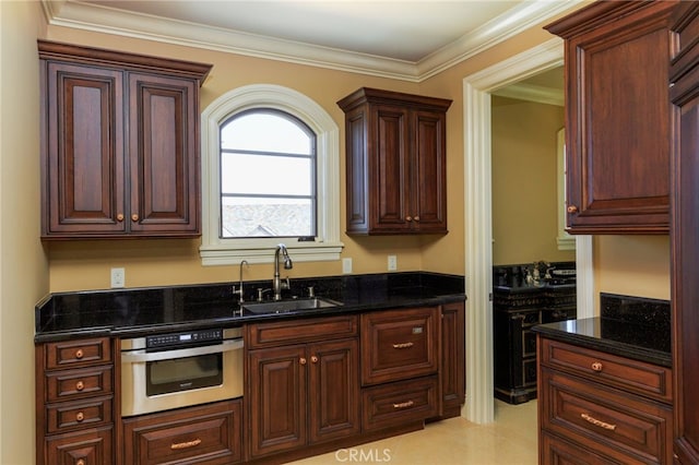 kitchen with dark stone counters, a sink, oven, and crown molding