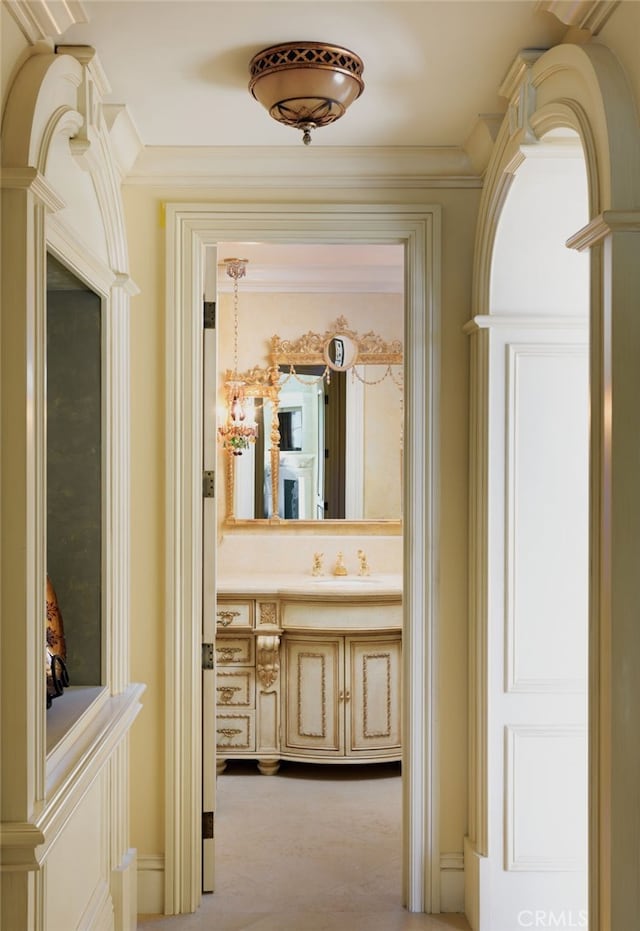 corridor featuring light carpet, a sink, and crown molding