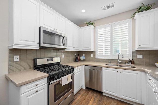 kitchen featuring dark wood-type flooring, a sink, visible vents, white cabinets, and appliances with stainless steel finishes