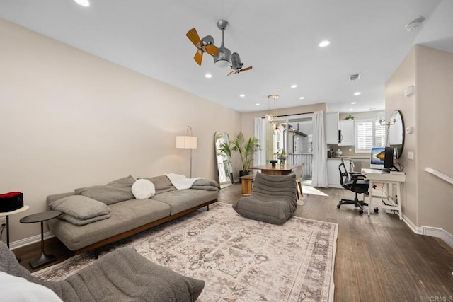 living room with a ceiling fan, visible vents, baseboards, and wood finished floors