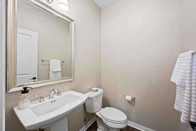 bathroom featuring baseboards, a sink, and toilet