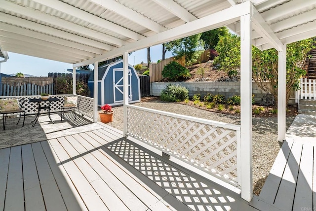 deck featuring a storage shed, an outdoor structure, and a fenced backyard