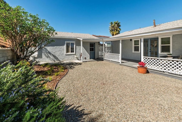 rear view of house featuring a patio area, fence, and stucco siding