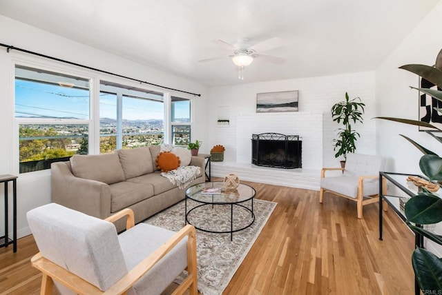 living room with a fireplace, a ceiling fan, and wood finished floors