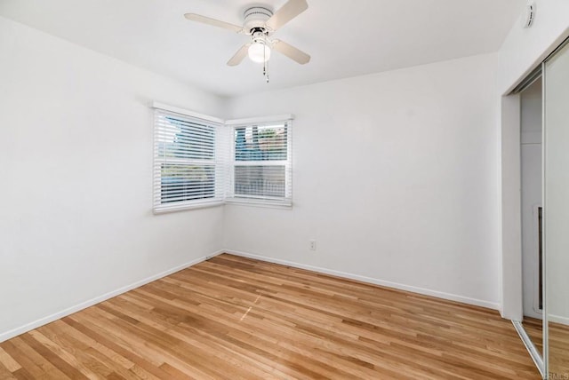 unfurnished room featuring a ceiling fan, light wood-type flooring, and baseboards